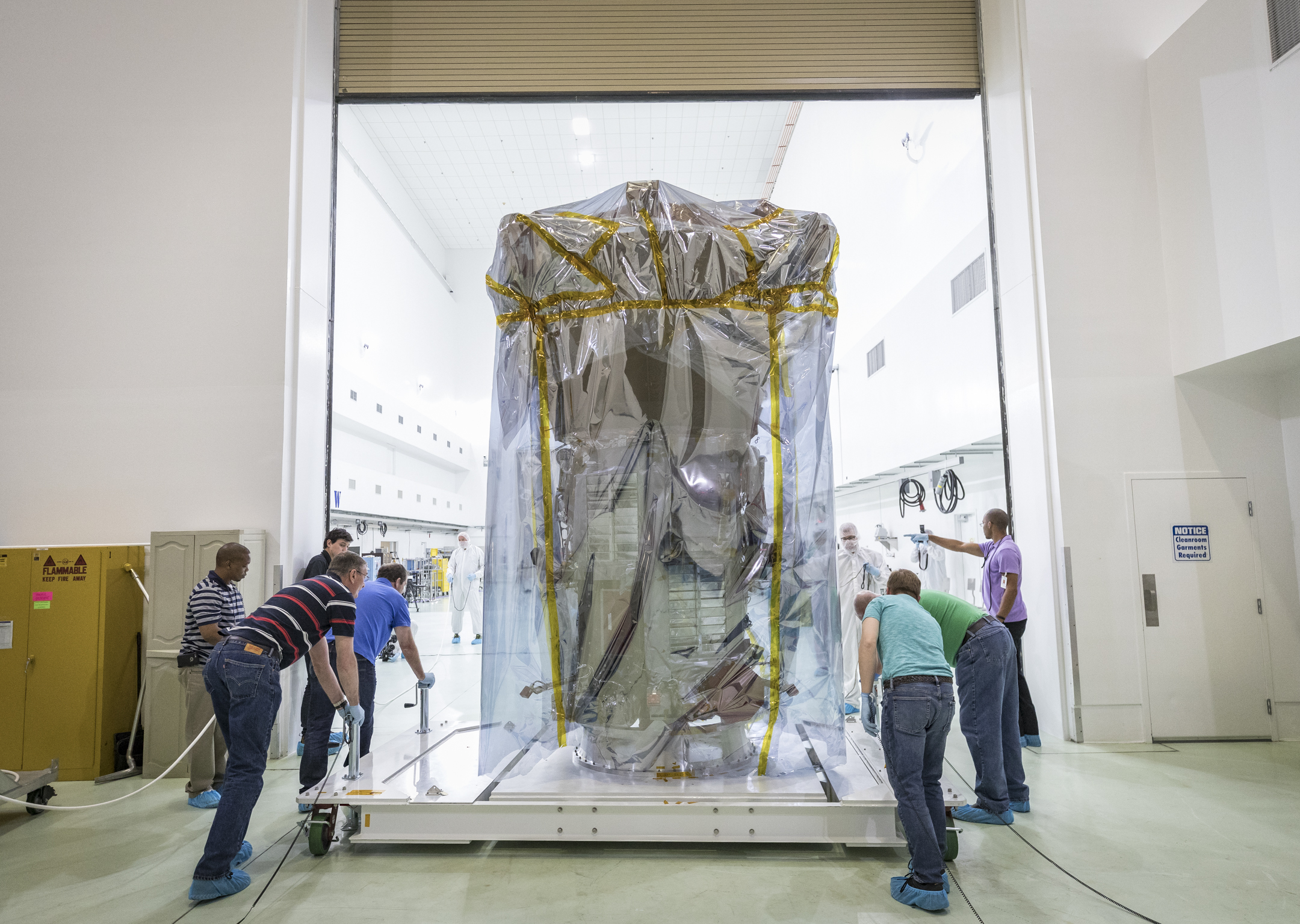 Protected by special plastic sheeting, NASA’s Parker Solar Probe is wheeled into a clean room at Astrotech Space Operations in Titusville, Florida, for pre-launch testing and preparations. On April 3, 2018, the spacecraft was transported from NASA’s Goddard Space Flight Center in Greenbelt, Maryland, to Joint Base Andrews by truck, then by a United States Air Force C-17 to Titusville. 