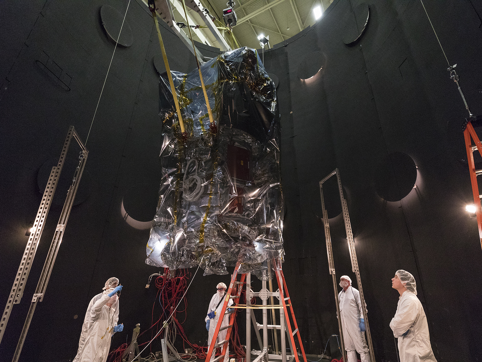 Engineers and technicians from the Parker Solar Probe team monitor the descent of the spacecraft into the thermal vacuum chamber. 