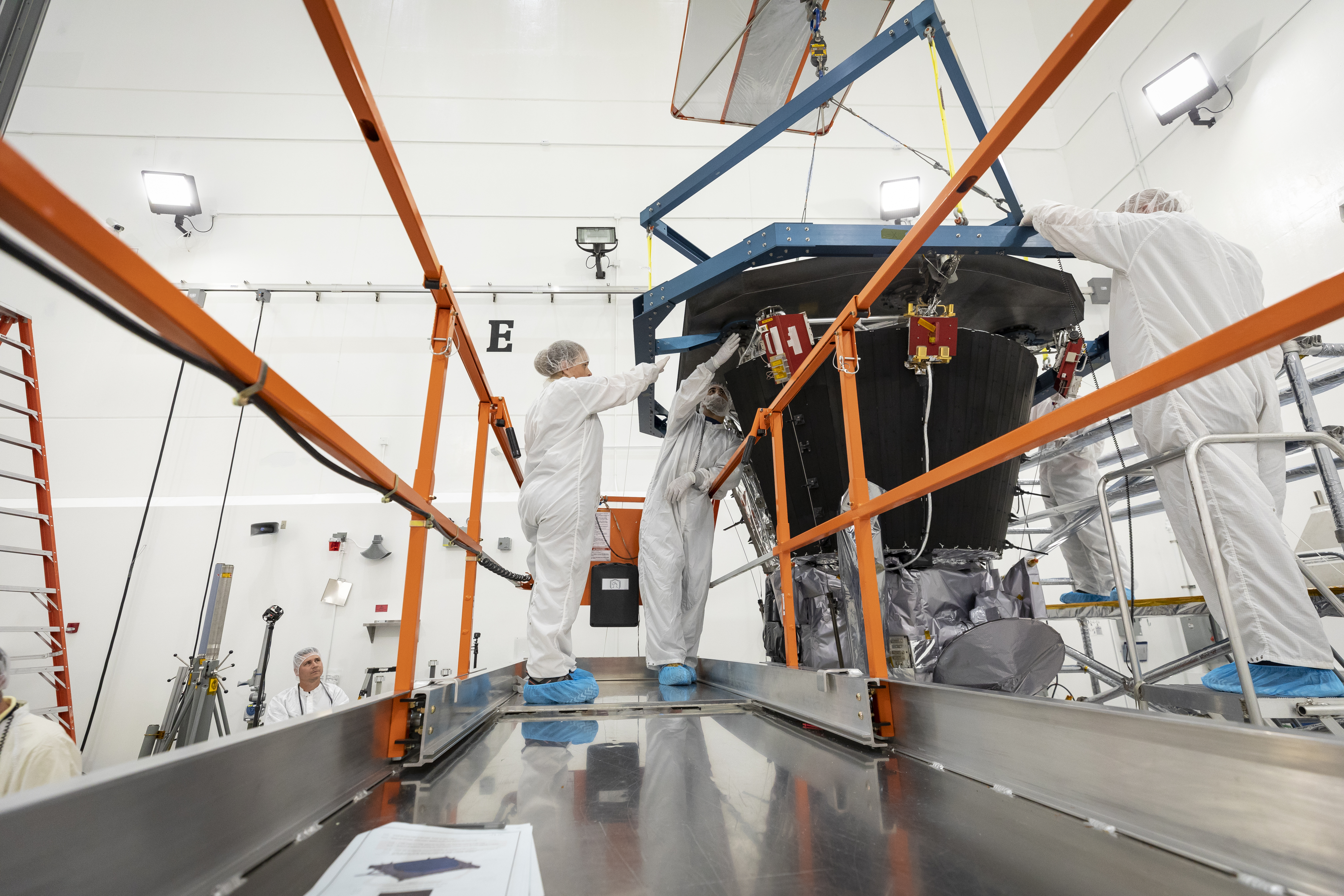 Parker Solar Probe’s heat shield, called the Thermal Protection System, is lifted and realigned with the spacecraft’s truss as engineers from the Johns Hopkins Applied Physics Lab prepare to install the eight-foot-diameter heat shield on July 27, 2018. 