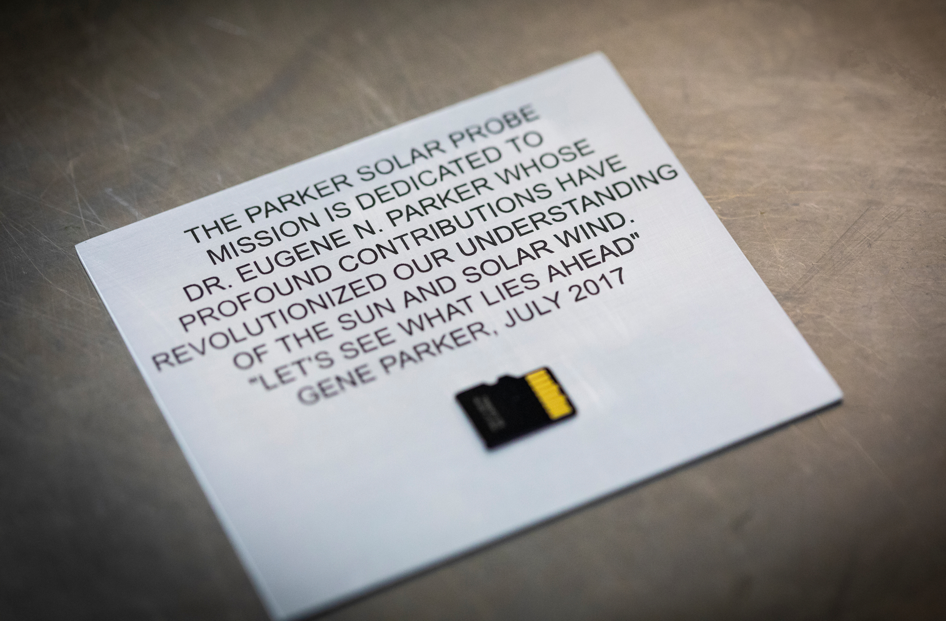 A plaque dedicating NASA’s Parker Solar Probe mission to its namesake, Eugene Parker, who first theorized the existence of the solar wind, was installed onto the spacecraft on May 18, 2018, at Astrotech Space Operations in Titusville, Florida. The memory card at bottom of the plaque contains 1,137,202 names submitted by the public to travel to the Sun aboard the spacecraft, along with photos of Parker and a copy of his groundbreaking 1958 scientific paper. Parker Solar Probe is the first NASA mission to be named for a living person.