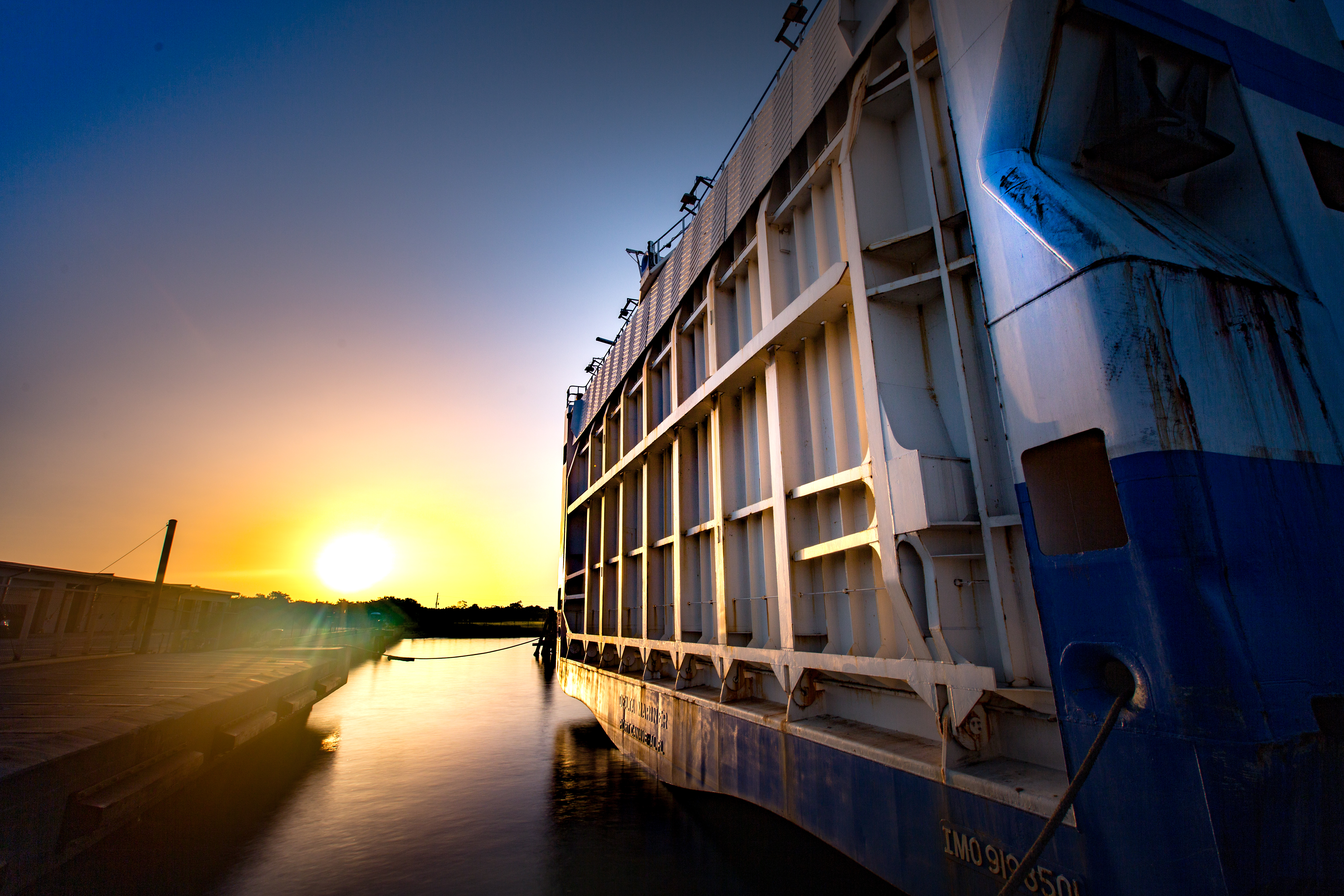 Sunrise is reflected in the side of the Mariner ship and in the water of Port Canaveral below. 